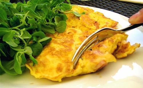 Omelet sa isang plato, tinidor at gulay