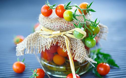 Green at pulang cherry kamatis sa isang garapon