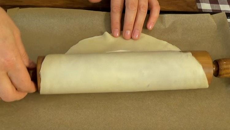 Gamit ang isang rolling pin, maingat na ilipat ang workpiece sa isang baking sheet na sakop ng parchment.