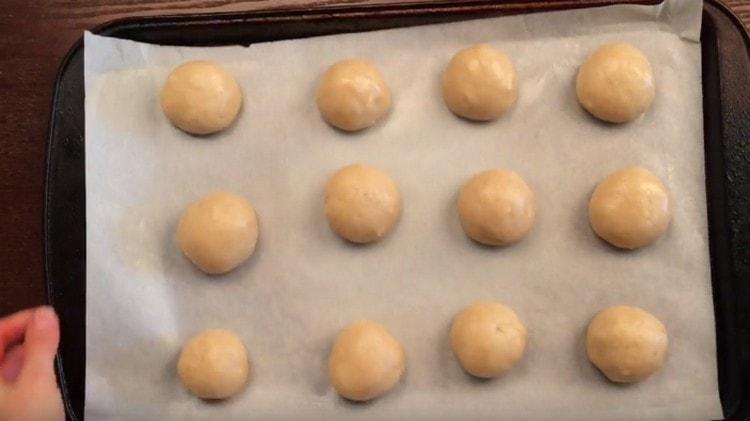 Sa mga basa na kamay, igulong namin ang mga bola mula sa masa at inilalagay ito sa isang baking sheet na natatakpan ng pergamino.