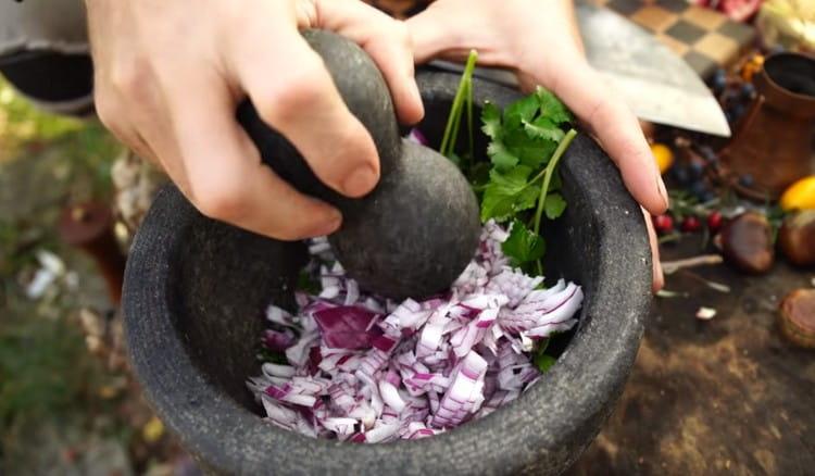 Magdagdag ng cilantro sa sibuyas at giling ang pareho ng mga sangkap na ito sa isang mortar.