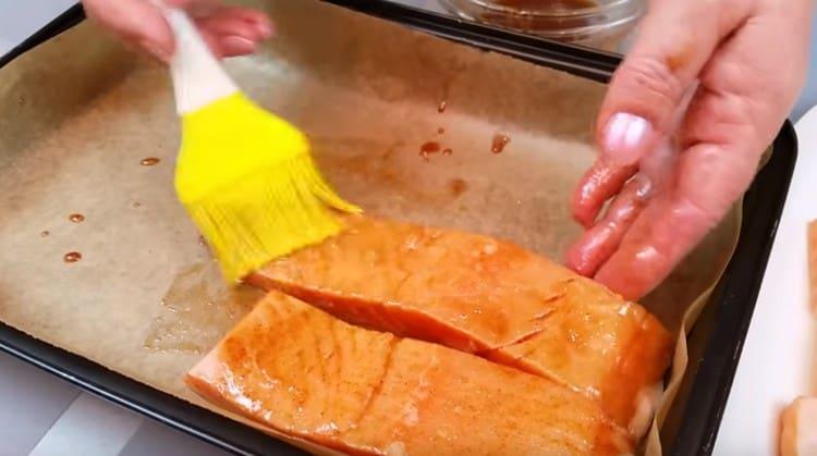 Sinasaklaw namin ang baking sheet na may pergamino, grasa ito ng atsara at inilatag ang mga piraso ng salmon, din ang pagpapahid sa kanila ng maraming atsara.