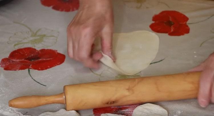 Pagulungin ang kuwarta sa isang sausage, gupitin at i-roll ang bawat isa sa kanila ng isang rolling pin.