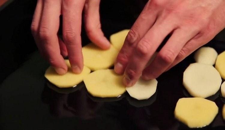 Ang pagkakaroon ng greased isang baking sheet na may langis ng gulay, kumakalat kami ng isang patong na patatas.