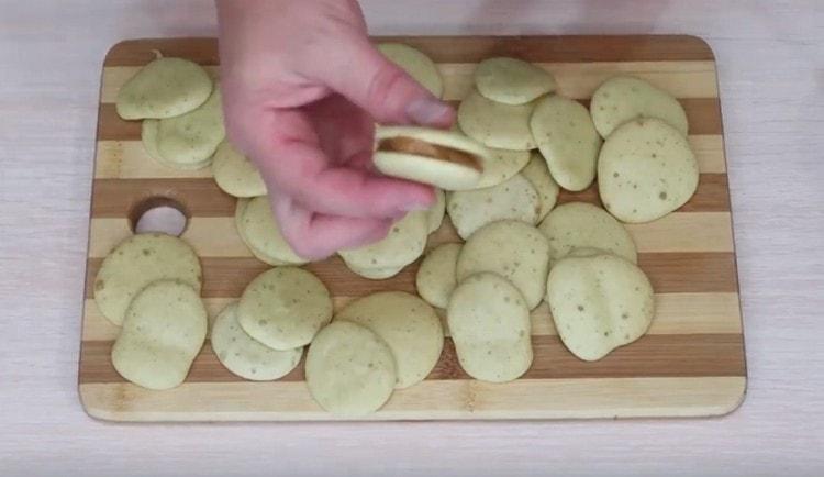 Kumuha kami ng dalawang cookies, grasa ang mga ito ng pinakuluang condensa ng gatas at pagsamahin.