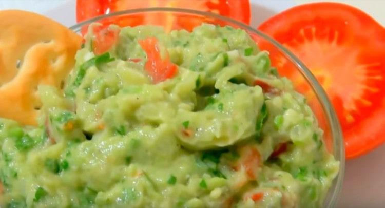 Ang sarsa ng Guacamole, na inihanda alinsunod sa klasikong recipe na may abukado, ay maaaring ihain sa iba't ibang mga meryenda.