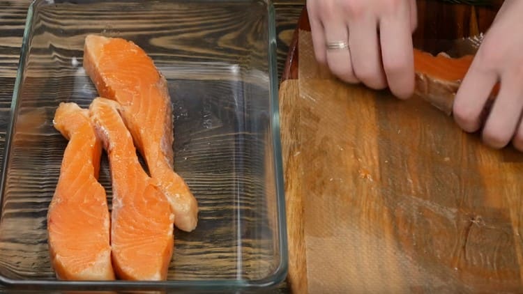 Ikinakalat namin ang mga piraso ng salmon na may isang baking dish na may mga gilid.