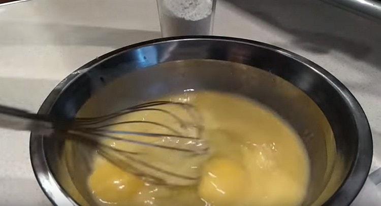 Magdagdag ng dalawang itlog sa mantikilya at matalo ng isang whisk.