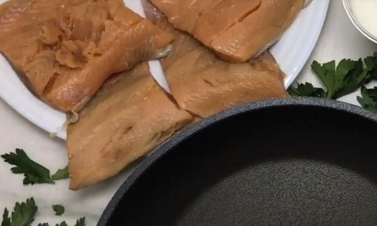 Gupitin ang fillet ng pink salmon sa maraming mga bahagi na piraso.