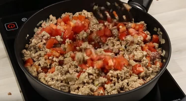 Aggiungi i pomodori alla carne tritata con le cipolle.