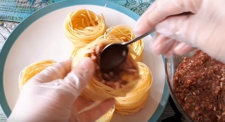 Pinupunan namin ang dry pasta nests na may tinadtad na karne.