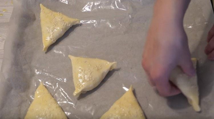 Ang pag-spray ng samsa na may mga linga ng linga, ikalat ito sa isang greased sheet ng pergamino sa isang baking sheet.