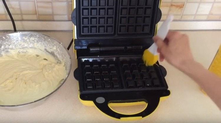 Pinapainit namin ang electric waffle iron, grasa ang mga form na may langis ng halaman.