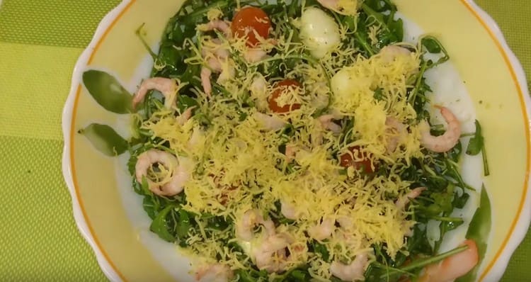 Handa na salad na may arugula, hipon at cherry kamatis iwiwisik ng gadgad na keso.