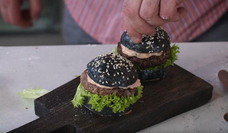 Naglagay kami ng ilang mga sarsa sa cutlet, takpan ang lahat ng ito ng isang bun, at handa na ang aming itim na burger.