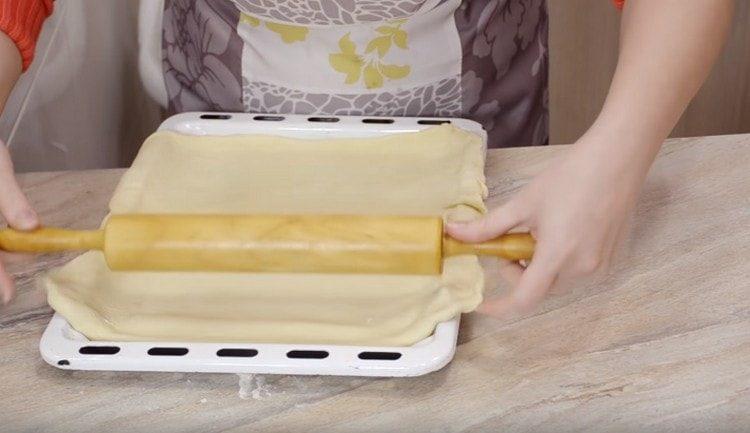 Inilipat namin ang kuwarta sa isang baking sheet at bumubuo sa base ng pie.