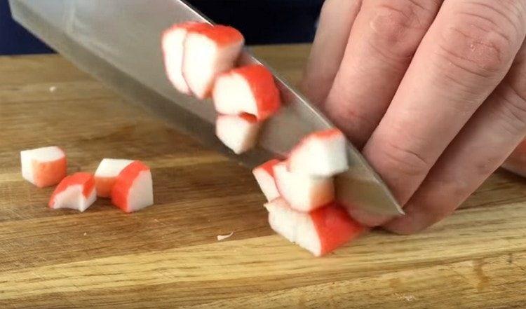 Gupitin sa mga piraso ng crab sticks.