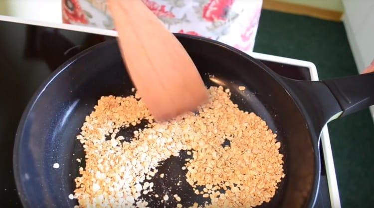 Ang Oatmeal ay gaanong tuyo sa isang dry frying pan.