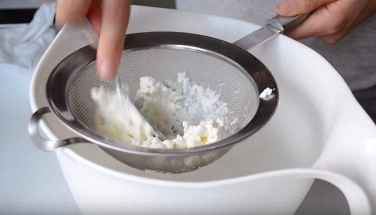 Kuskusin ang cottage cheese sa pamamagitan ng isang salaan.