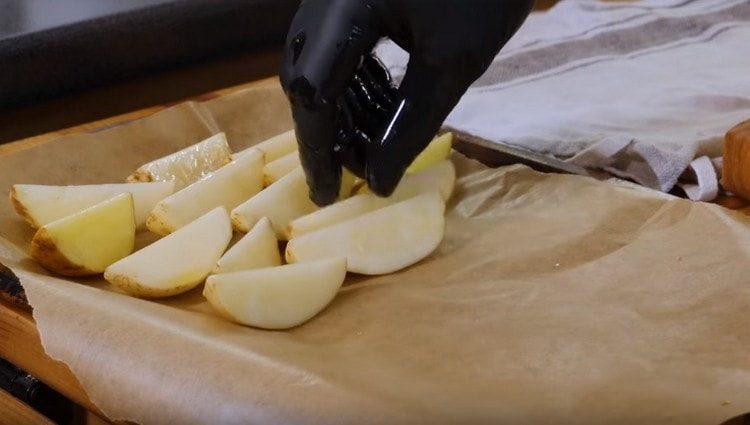 paglalagay ng isang baking sheet na may pergamino, ilagay ito sa mga wedge ng patatas.